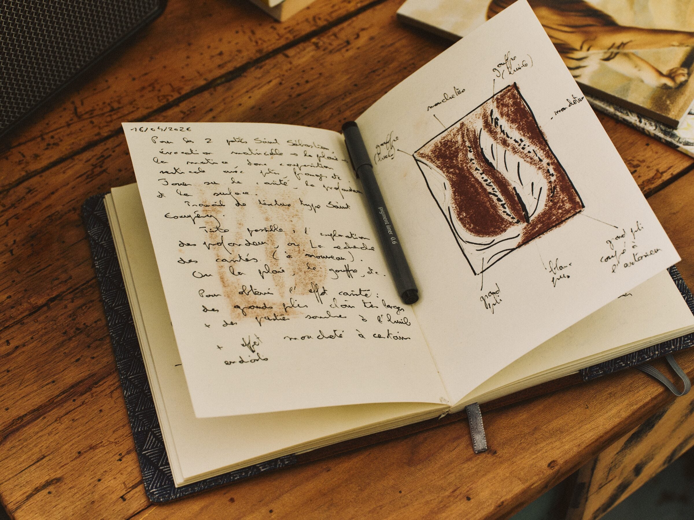 Aufgeschlagenes Skizzenbuch von Silvère Jarrosson auf einem Holztisch